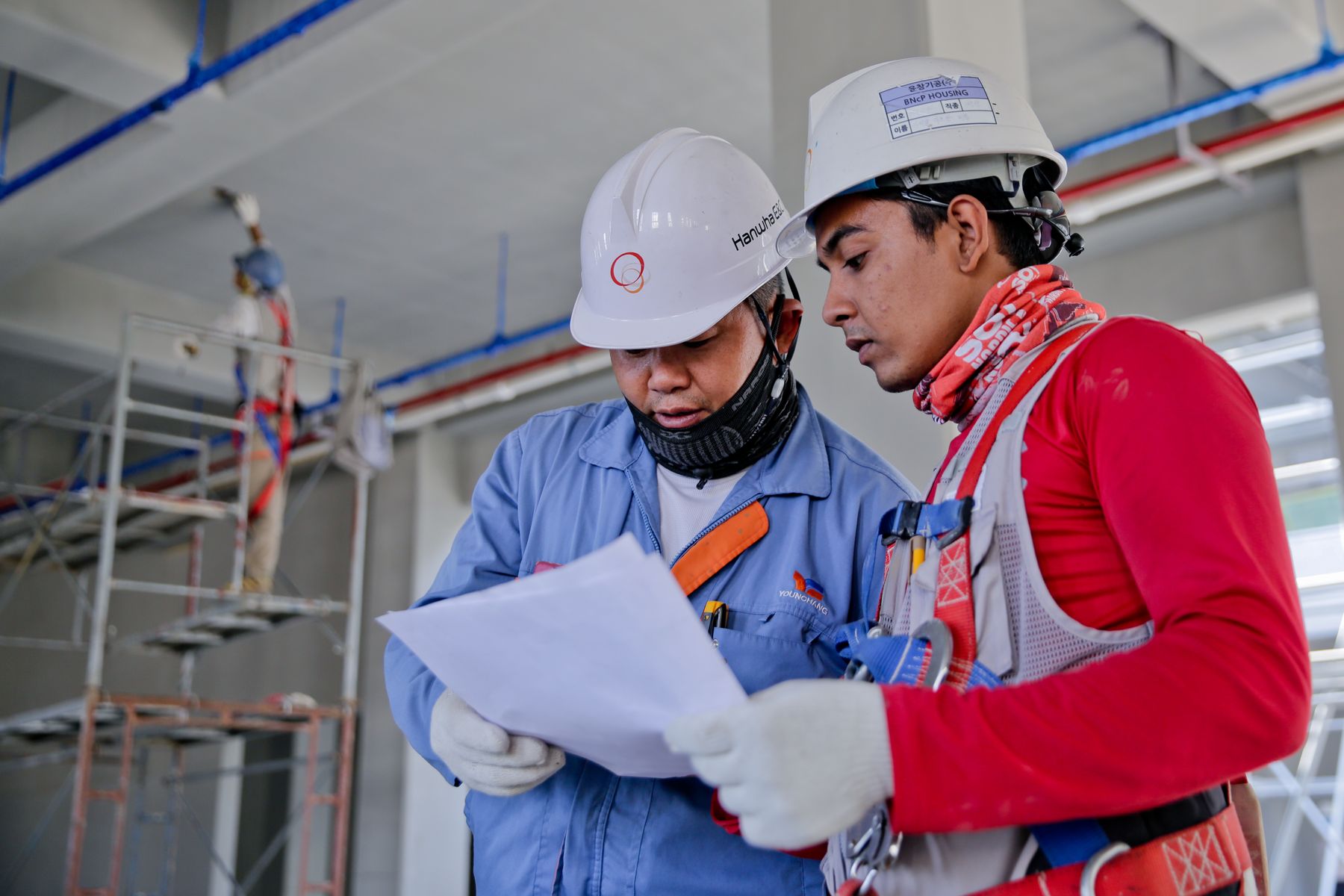 Two site engineers reviewing blueprints inside a building under construction